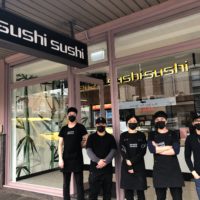 Sushi Sushi franchise employees stand in front of store