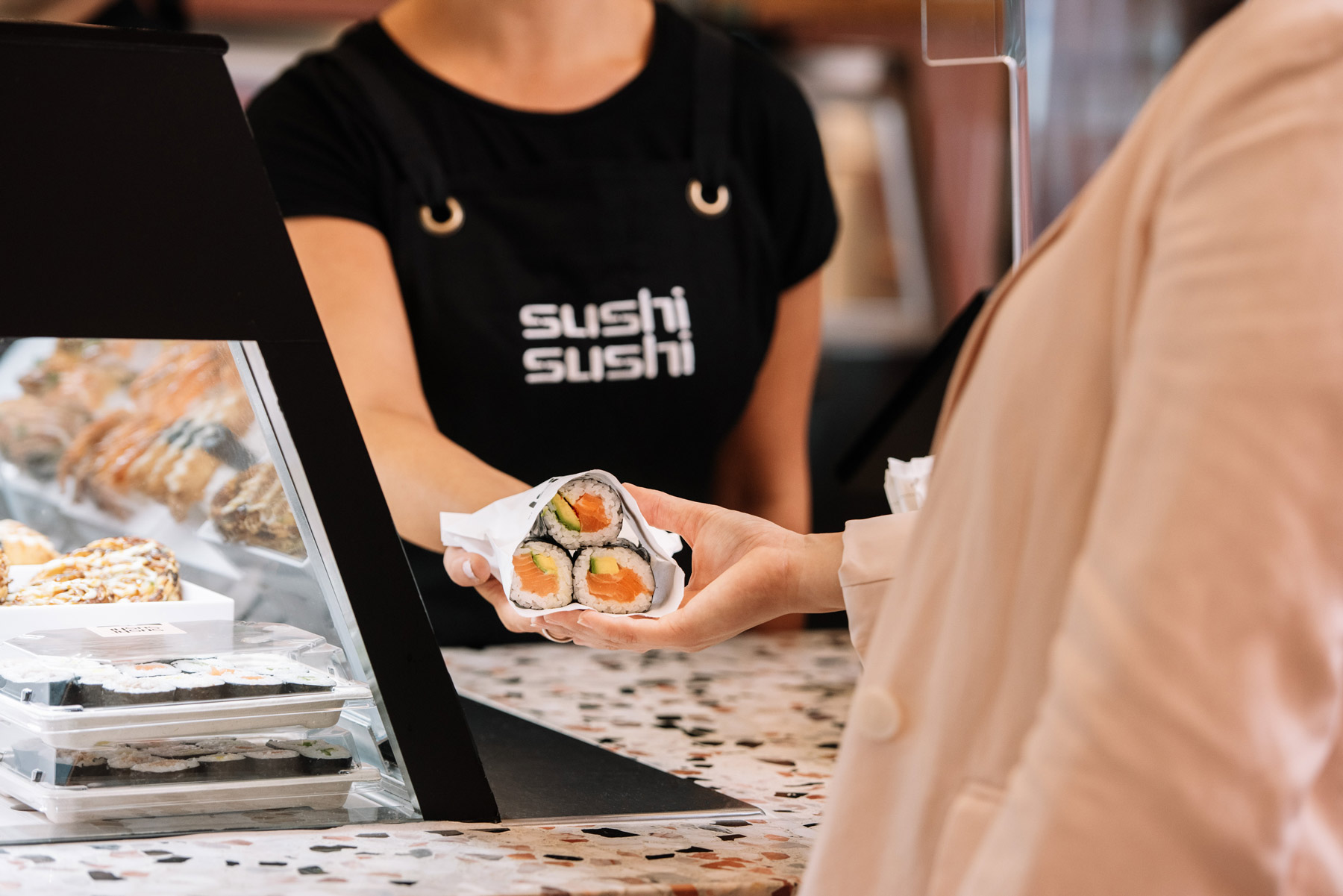 Sushi Sushi Franchise employee hands customer sushi